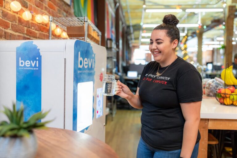 Young woman with hair in a bun getting water from a Bevi machine