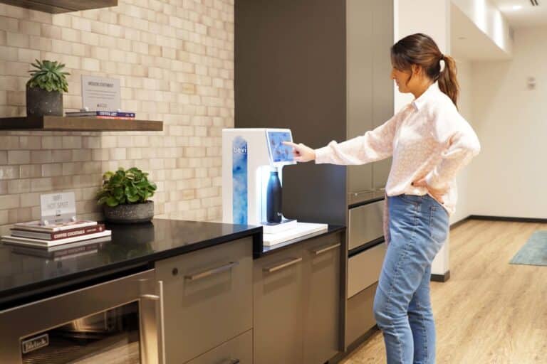 Woman using the Bevi Countertop machine in an apartment amenity lounge