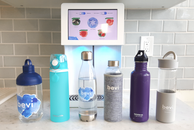 Several reusable water bottles on a counter in front of a Bevi Countertop machine