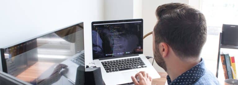 Over-the-shoulder view of man working on laptop