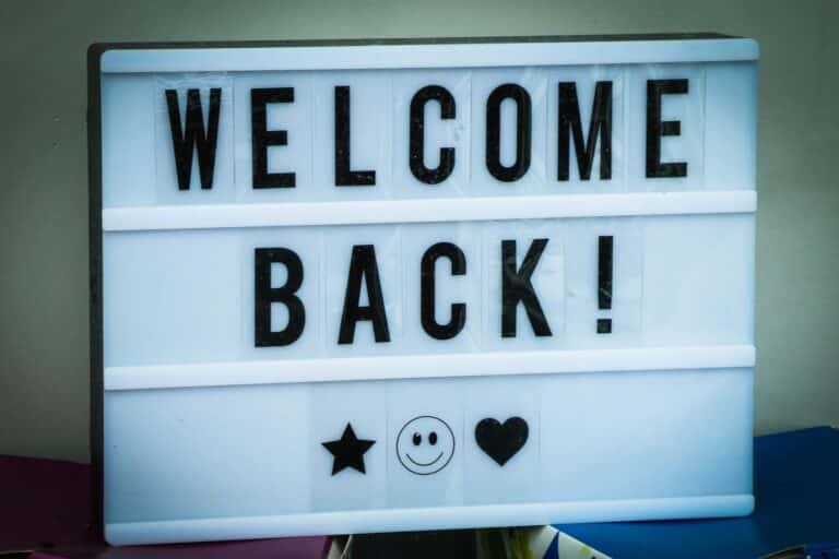 White sign with black letters that says "Welcome Back!"