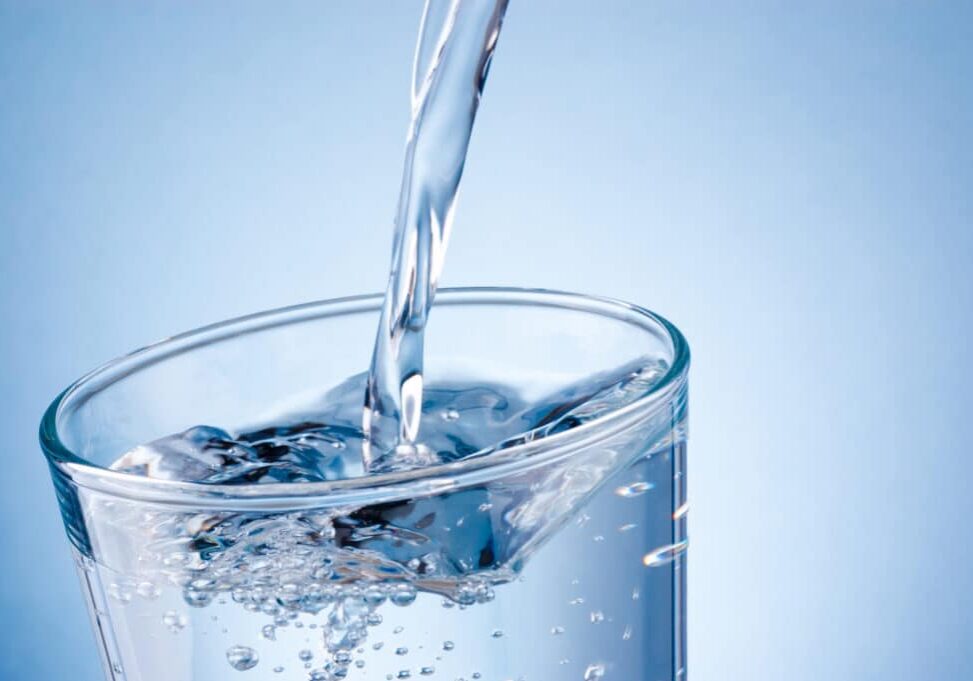 Pouring water into glass on a blue background