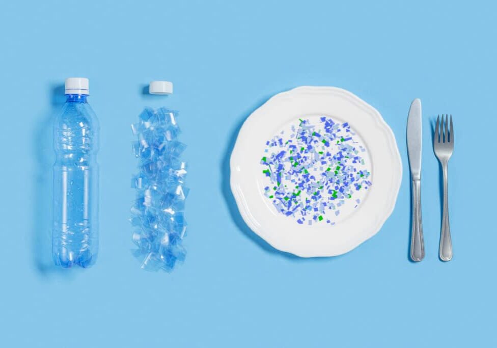 White plate full of microplastics on blue background with copy space. Plastic pollution concept, global ocean pollution ecology problem, microplastic particles in water and food, top view, flat lay