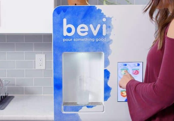 Woman in a maroon sweater standing in front of a Bevi standup machine