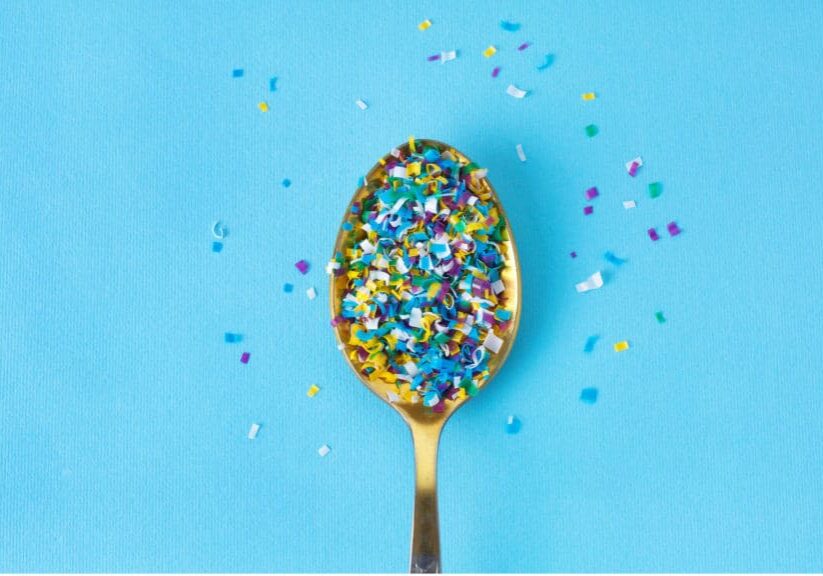 Spoon filled with small, colored bits of micro plastics