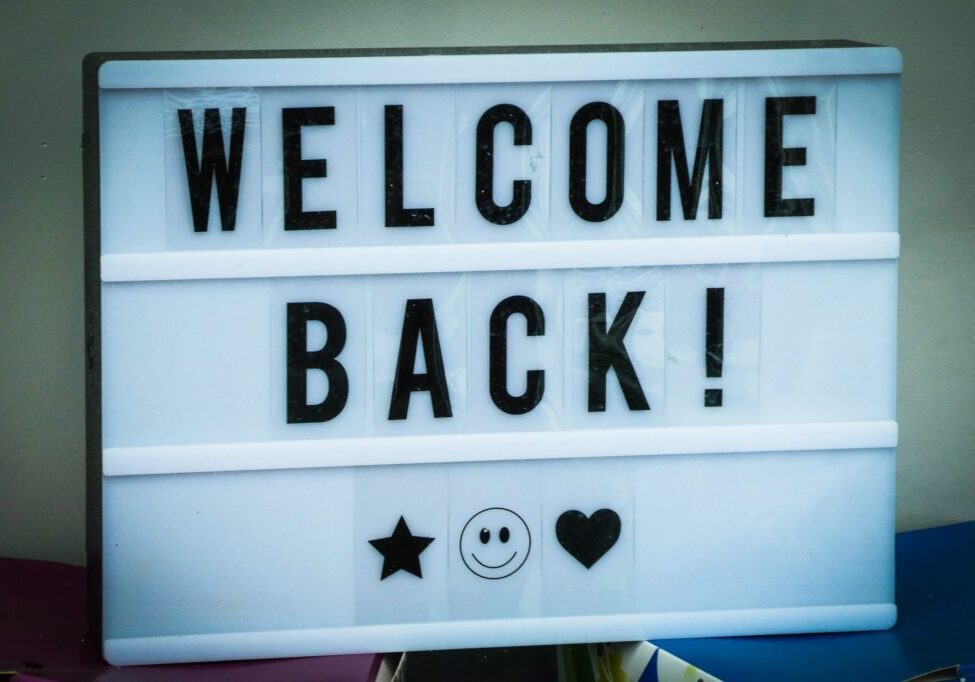White sign with black letters that says "Welcome Back!"