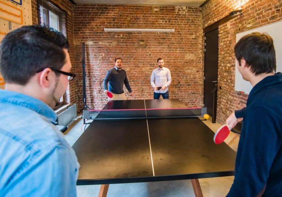 4 men playing ping pong in an office